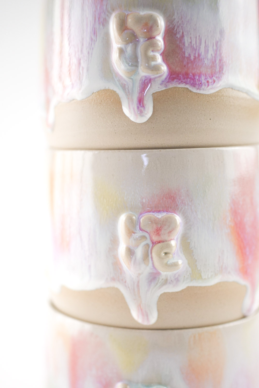 Handgefertigte Tasse mit erhabenem "love" Schriftzug und bunter Glasur